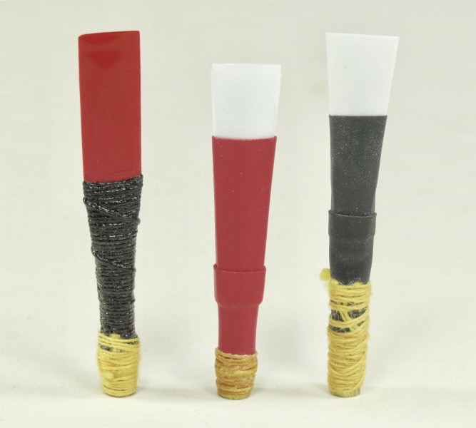 A group of practice chanter reeds shown close up. Small, narrow cane reeds bound to a short staple.